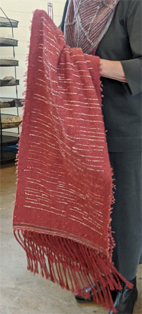 After admiring fabric Donna wove with a type of novelty yarn back in December 2018, Shelby was able to obtain a supply of the yarn and wove this shawl using it as weft with a rayon warp. The novelty weft has a nylon core with added tufts. The closeup shows the back has no tufts because Shelby manipulated the tufts, pick by pick, to put them on the front surface.